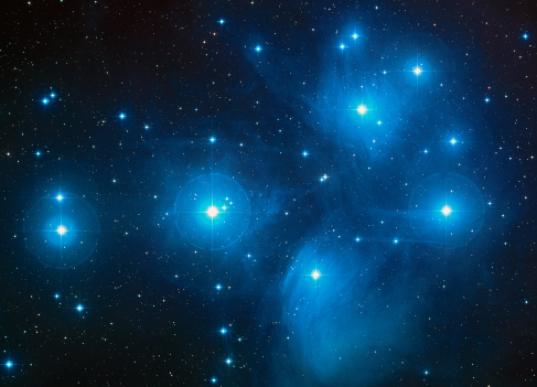 The Pleiades. The light from the bright, blue stars of this cluster reflects off of the nearby dust clouds, giving the appearance of streetlamps on a foggy night.