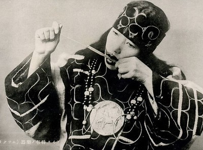 Ainu woman with mouth tattoo playing mouth harp called mukkuri