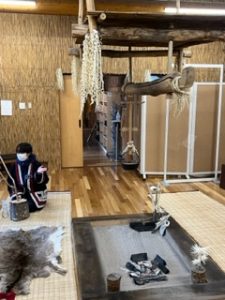woman seated beside traditional Ainu hearth