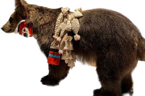 Bear cub decorated with woven charms around upper back and neck