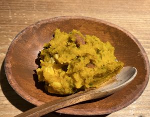 yellow pumpkin-based food on wooden dish with spoon