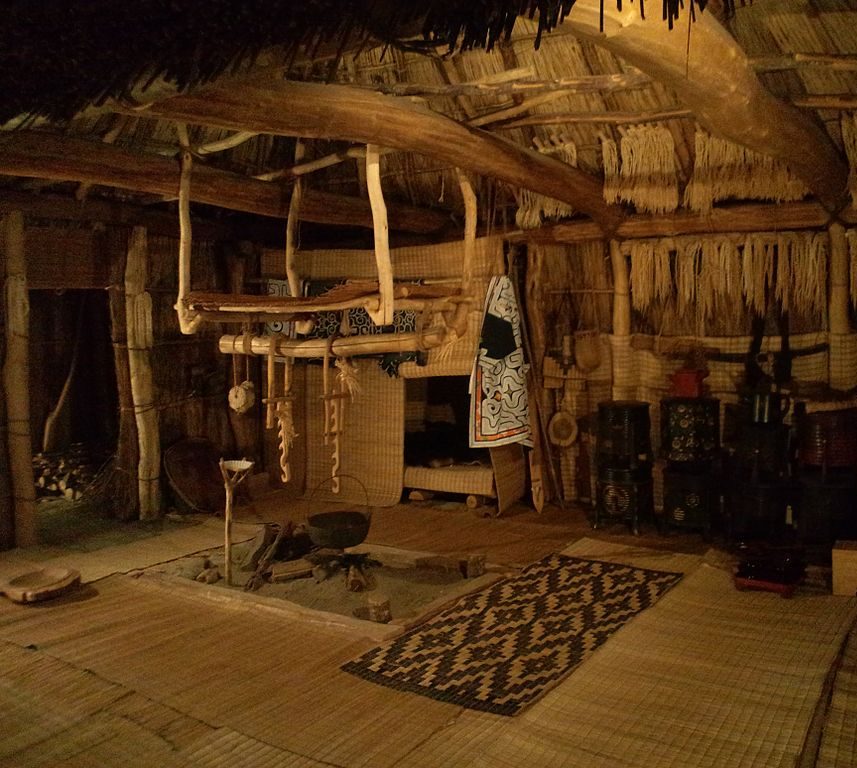 Interior of traditional Ainu house showing hearth, woven mats and cooking utensils