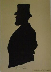 Silhouette: Half-length bearded male figure in top hat, in left-facing profile; black paper cut-out mounted on cream paper; rectangular black-painted wood frame.