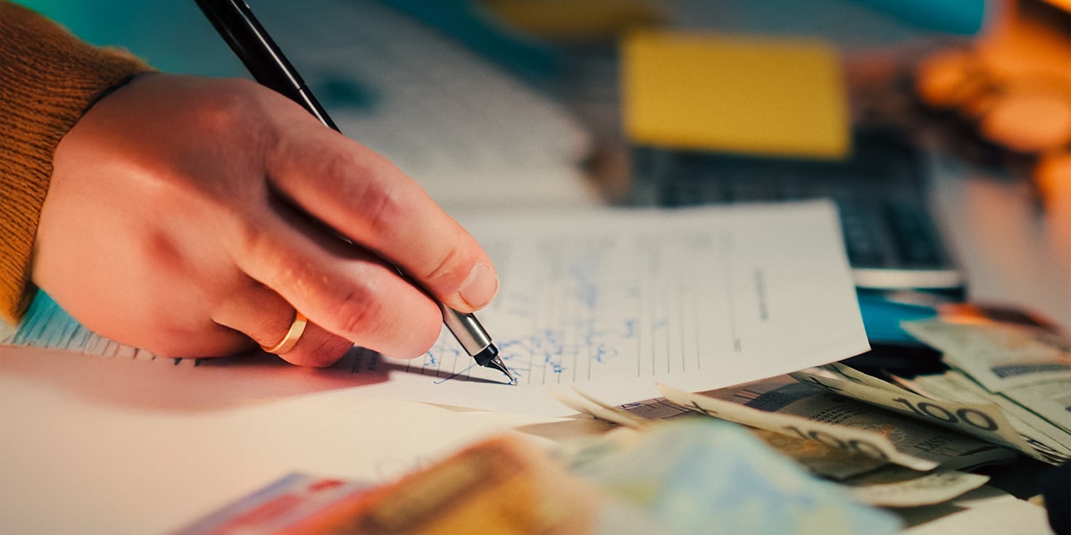 Hand writing financial notes with documents, representing financial planning for trades businesses