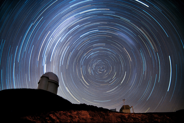 Photograph of Stars Circling the South Celestial Pole. In this time-exposure photograph the stars are not seen as points of light, but as semi-circular arcs due to the rotation of the Earth during the exposure. The domes of several telescopes are silhouetted against the sky.