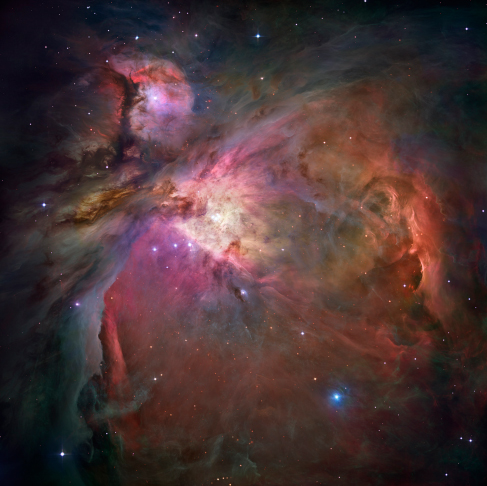 Photograph of the Orion Nebula. This image is dominated by large areas and bright swirls of glowing gas clouds, criss-crossed by dark bands of dust.