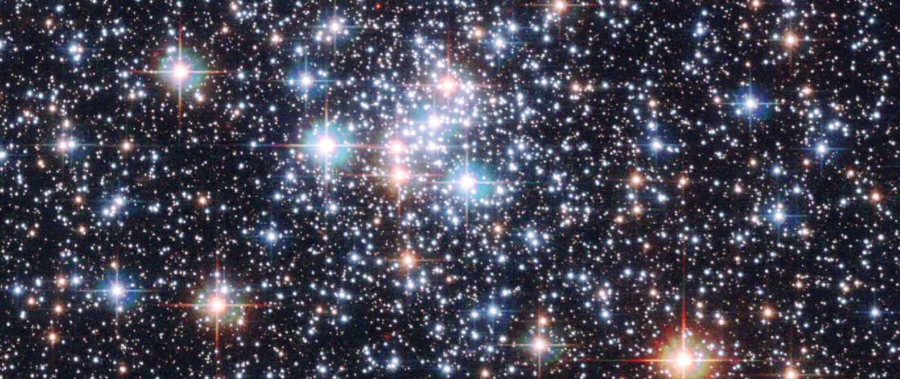 Image of NGC 290 in the Small Magellanic Cloud. In this photograph of a dense star cluster, the colors of the various types of stars comprising the cluster are evident. The colors range from white and light blue for the hottest stars, yellow for the intermediate temperature stars, and to red for the coolest stars.