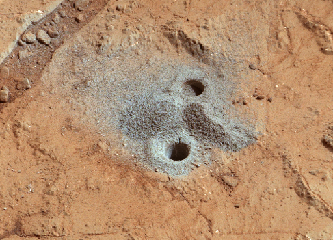 Mudstone on Mars. Close-up of the first drill holes by the Curiosity Rover. The grey material piled around the holes at the center of the photograph are in stark contrast to the typical red martian surface.