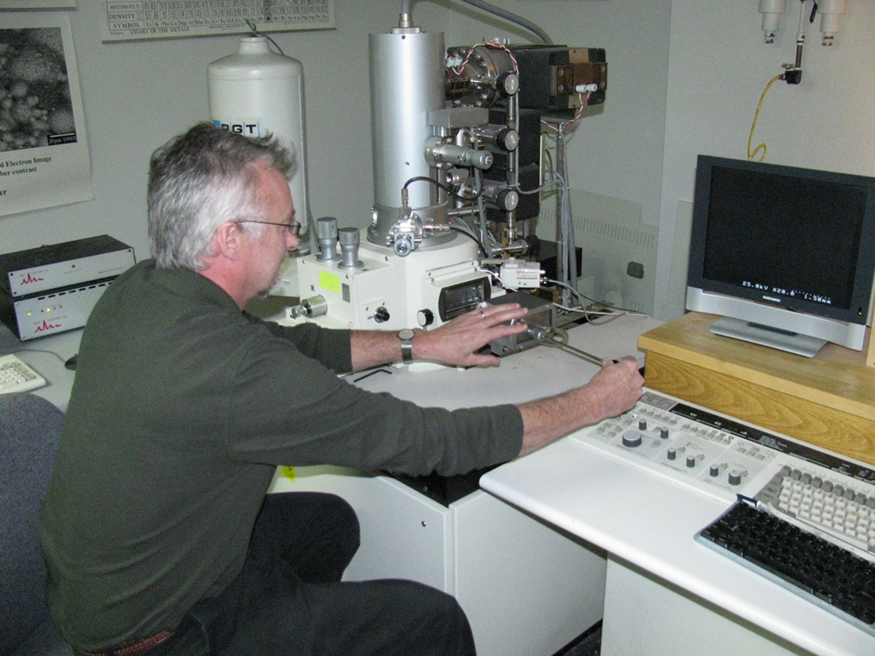 Image depicts a man using scanning electron microscope.