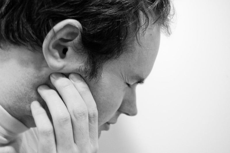 person clutching jaw, just below the ear