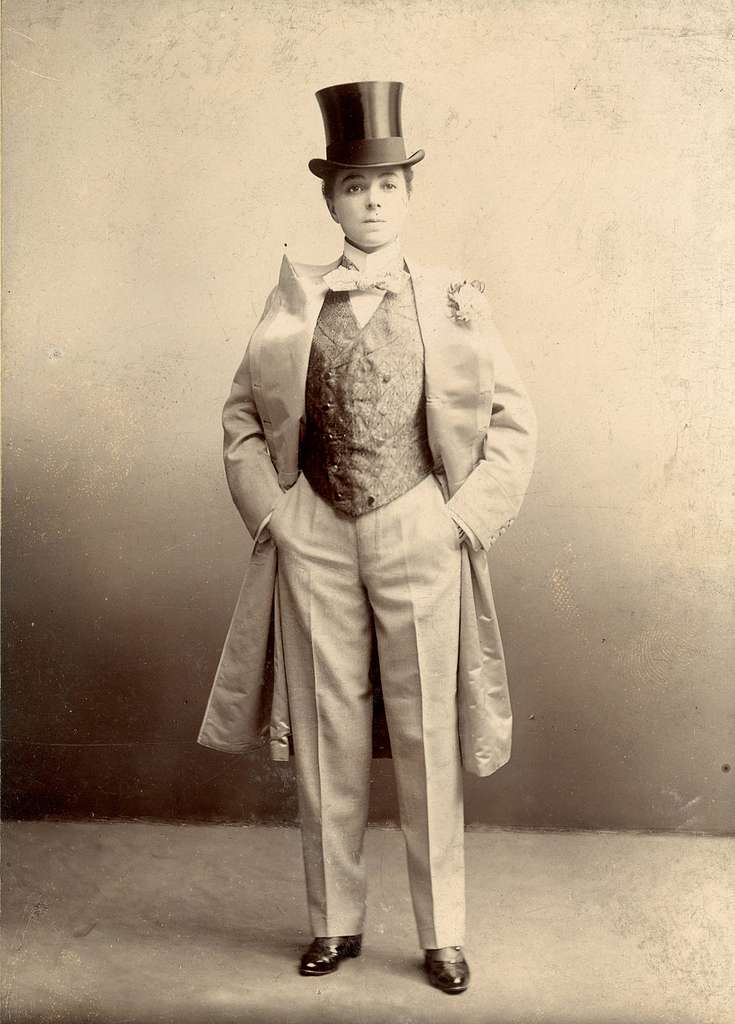 Photo of Vesta Tilley, a male impersonator wearing a top hat, vest and trench coat