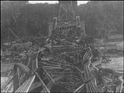 Black and white photo of twisted wreckage of a bridge.
