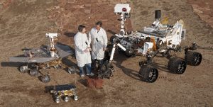 Engineers standing with Mars rovers 2012-01-17 - Two spacecraft engineers stand with three generations of Mars rovers. (Credit: NASA/JPL-Caltech)