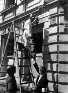 Photo of workers removing street signage from a former "Adolf Hitler-Staße" in Trier, Germany.