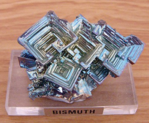 Hopper-shaped crystals clustered together. The crystals are silver and metallic in appearance, but with an iridescent sheen.