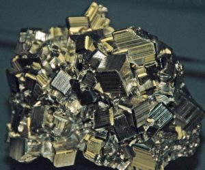 A mass of metallic cubes with striated surfaces and a dull gold colour.