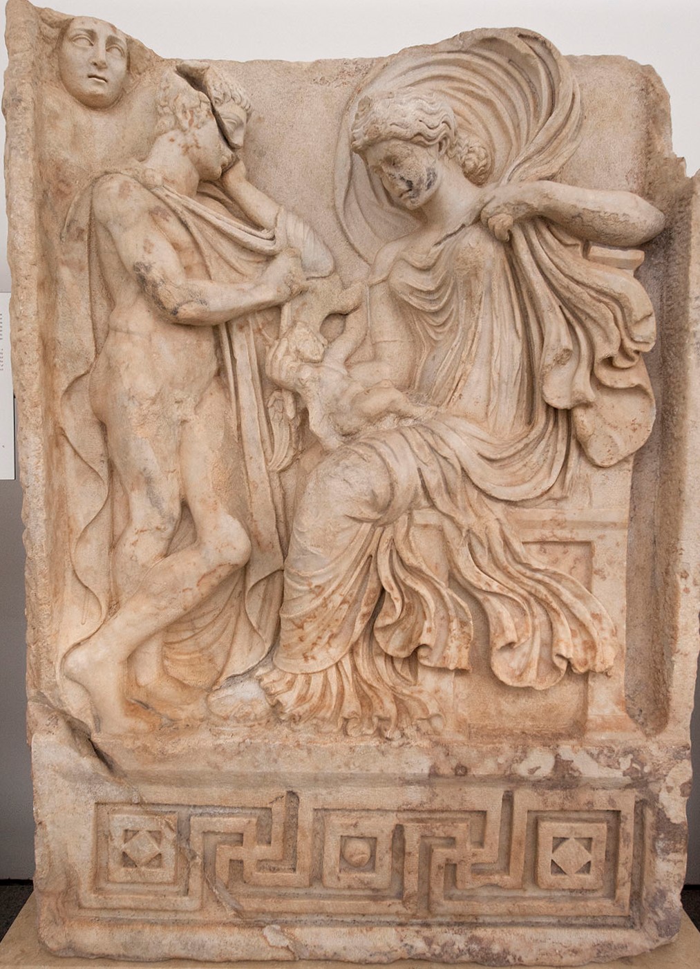 A relief of Aphrodite seated with a baby Aeneas on her lap, Anchises standing in front of her.