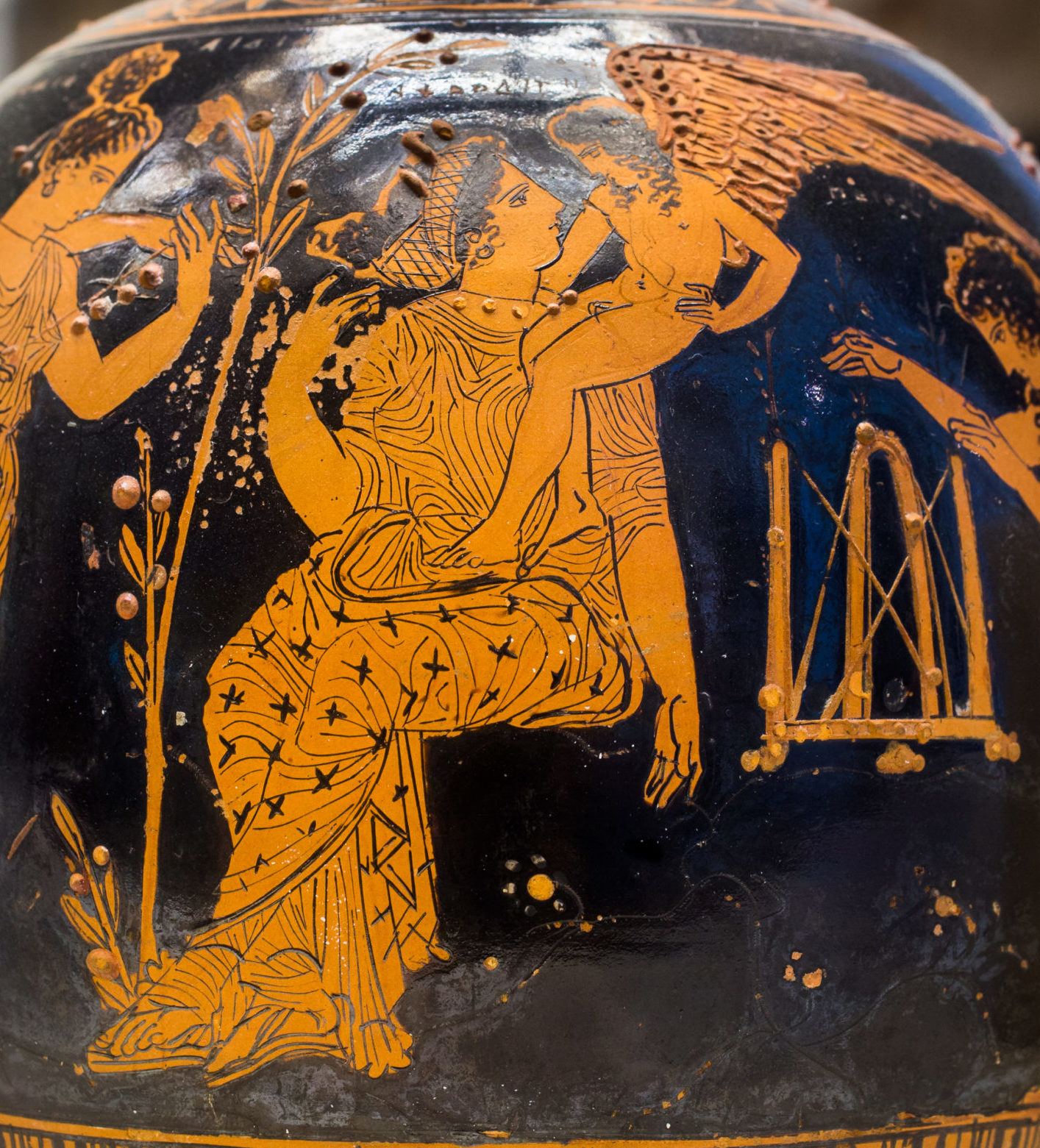 Aphrodite is seated with a small figure of winged Eros on her shoulder. She sits beside a tall myrtle branch, and two female figures flank her.