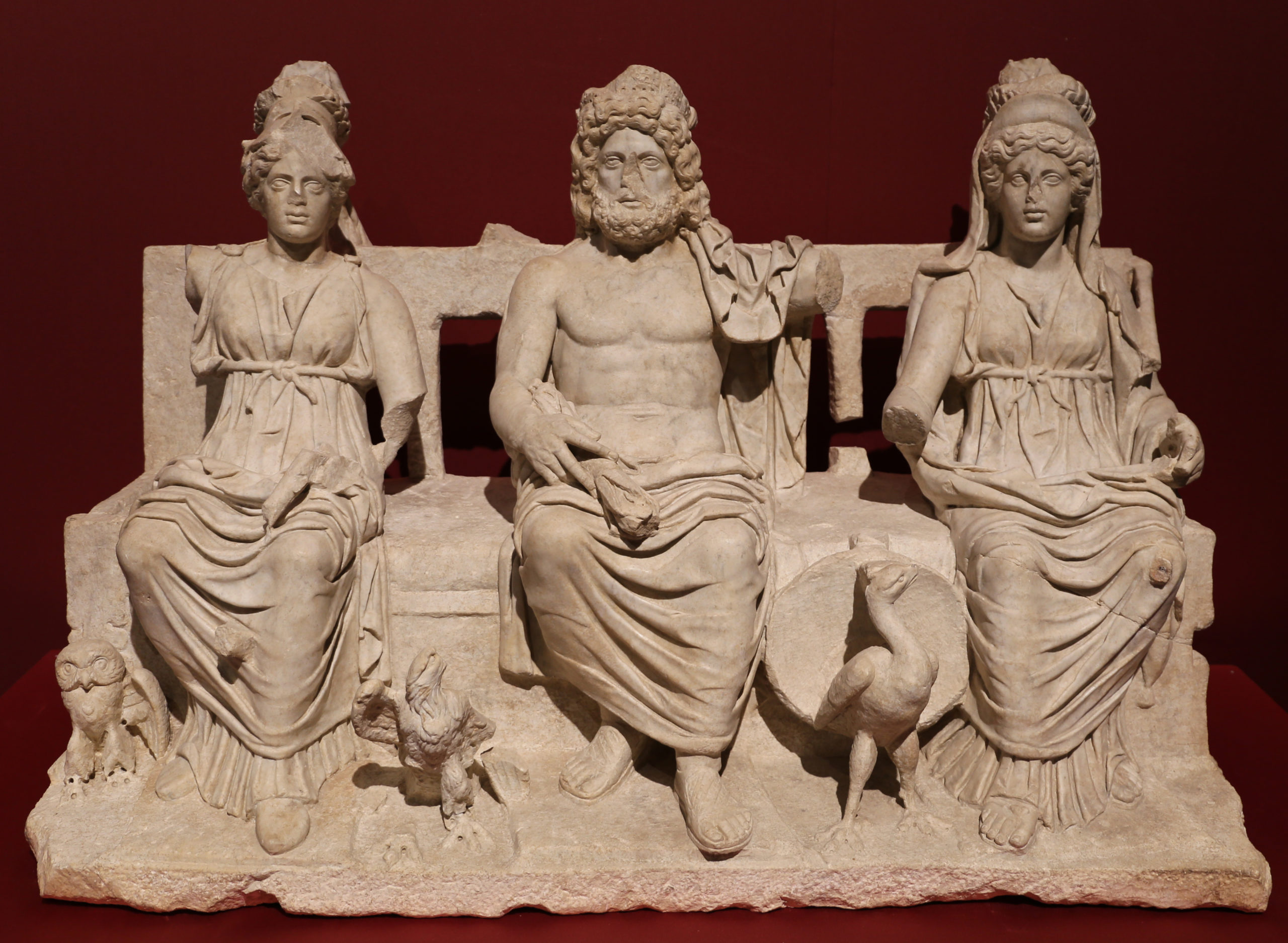 Seated robed figures of Minerva, Jupiter, and Juno. Each has a symbolic bird at their feet: Athena an owl, Jupiter and eagle, and Juno a peacock.