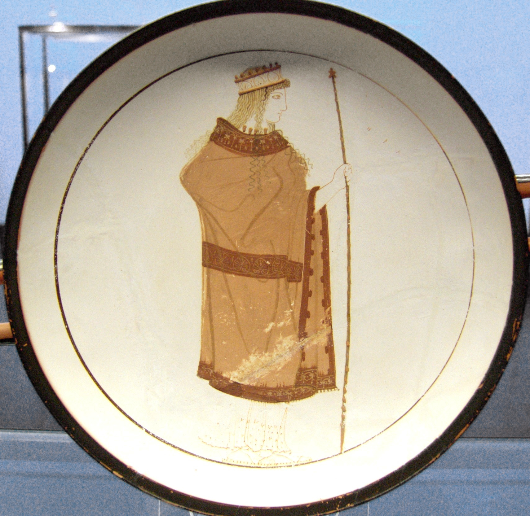 A circular white-ground pottery depiction of Hera, robed, wearing a crown, and holding a tall sceptre.