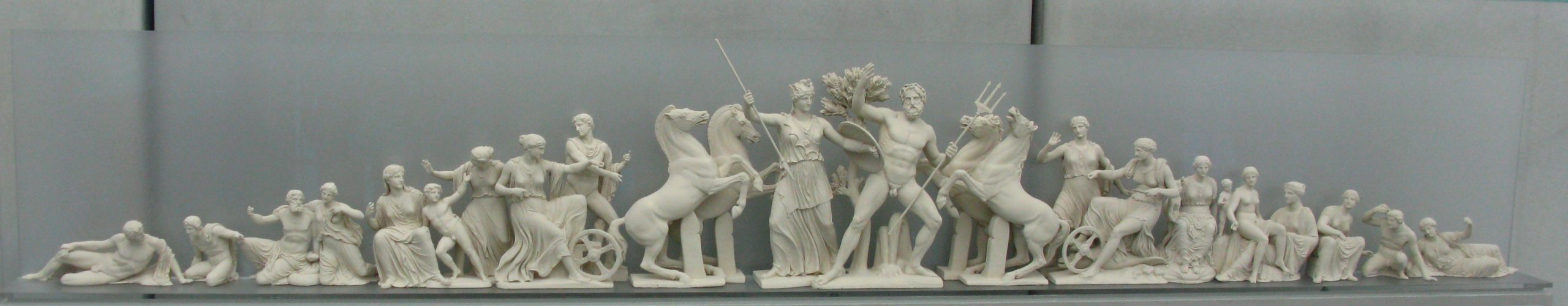 In the centre, Athena and Poseidon with an olive tree. They are flanked by horses and chariots on either side, as well as a number of human figures.