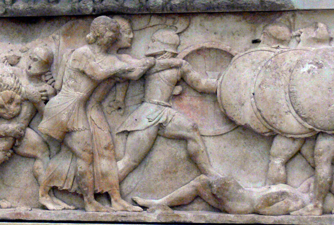 Apollo and Artemis lunge forward, side by side, to grab a fleeing giant. A dead giant lies on the ground, and three more armoured giants with shields approach from the right.