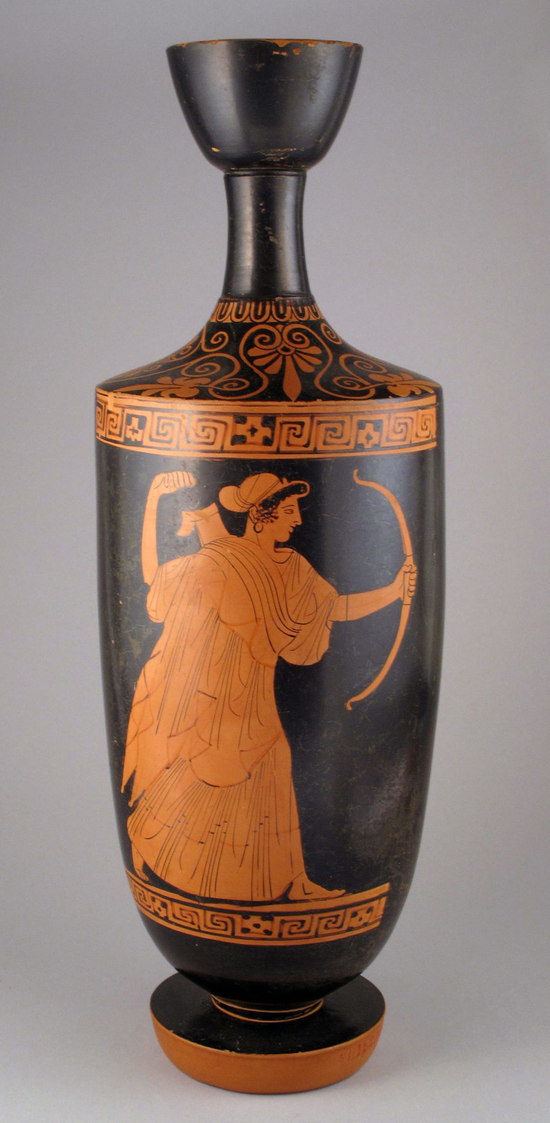 Artemis striding forward holding a bow in one hand and drawing an arrow from a quiver on her back.