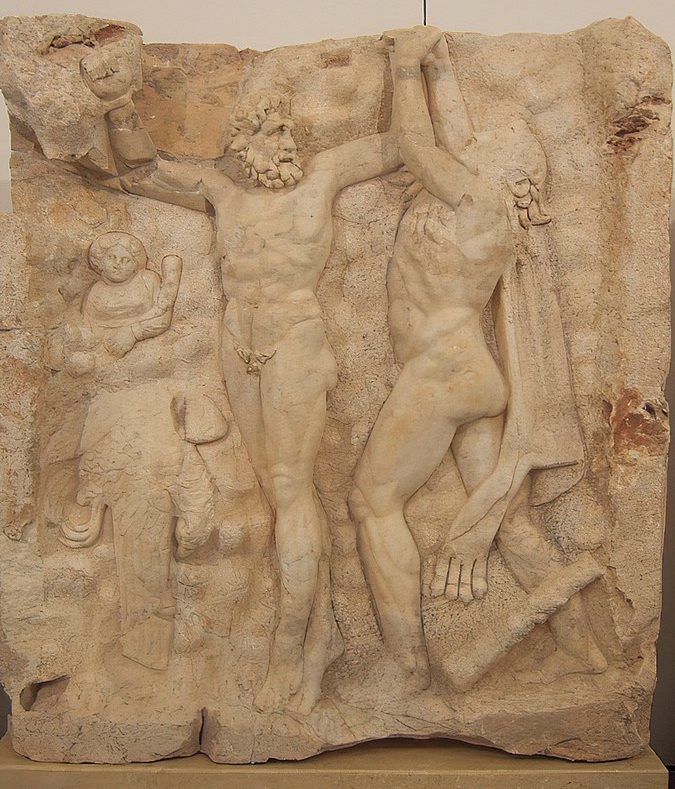 Prometheus, naked, stands with his arms bound above his head. To his right, Heracles reaches up to free Prometheus' hand. To Prometheus' left is the eagle, dead, and the small figure of a woman.