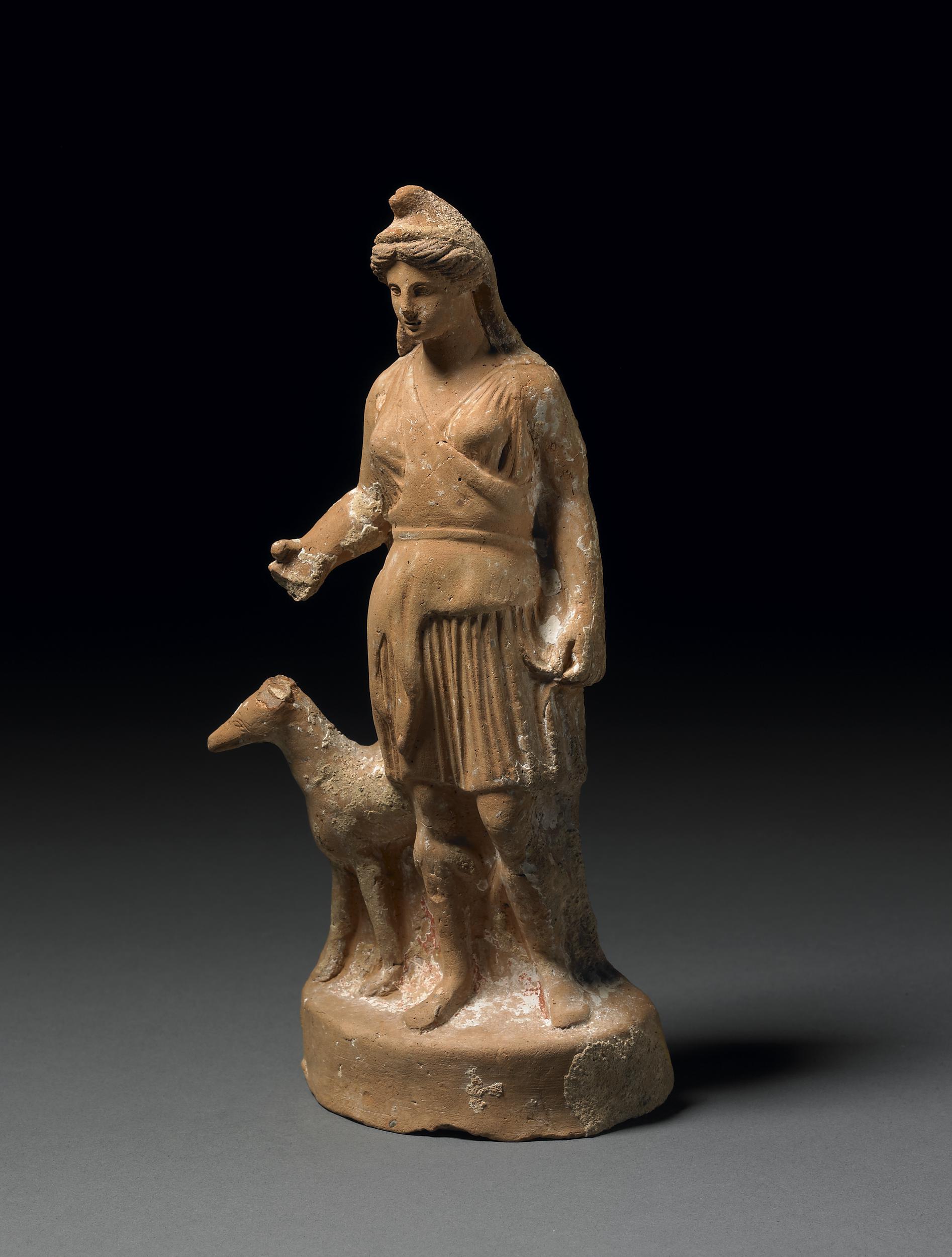 Artemis standing with a deer. She is a young robed woman and wears a conical Phrygian cap.