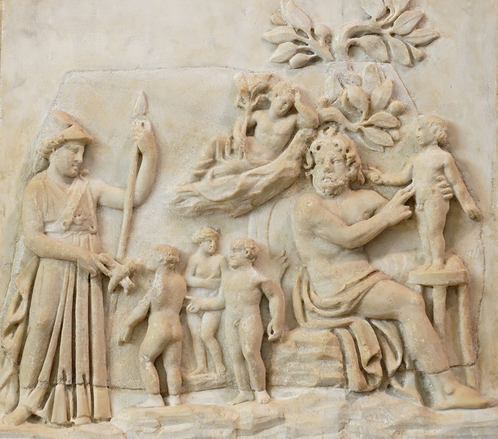 Prometheus, a nude bearded man, sits and sculpts a small person of clay. Behind Prometheus stand 3 more small people, freshly-made. Prometheus is sitting underneath a tree, in which sits another small figure. On the lefthand side stands Athena, holding a sceptre and wearing a helm.