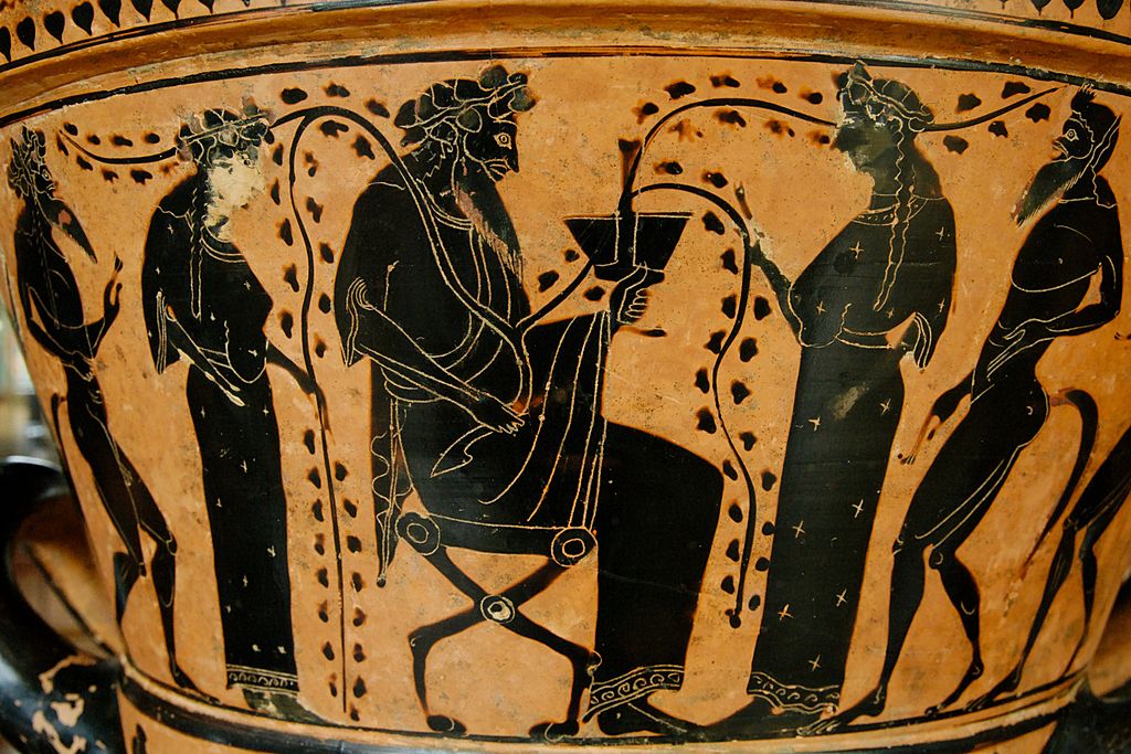 Dionysus, bearded and robed and wearing a crown of vines, sits and holds a cup. Vines flow from his hand and swirl around two women and two men who wait on him.