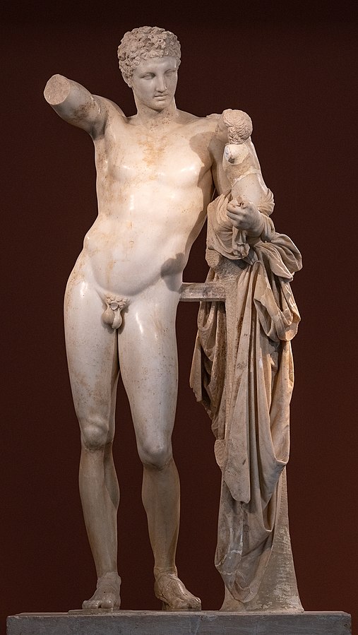 Hermes standing in the nude, holding a small infant Dionysus in his left arm.