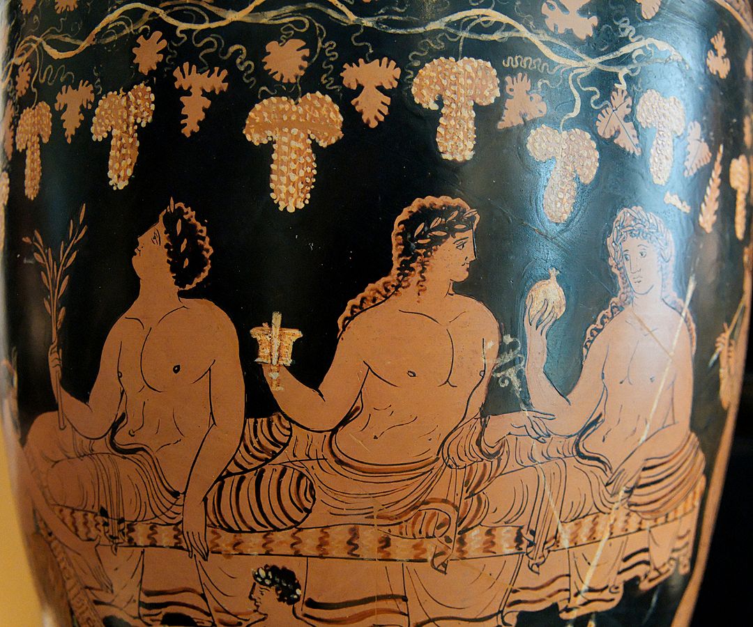 Dionysus, youthful with long hair and wearing a crown of laurels, reclines on a bench holding a cup. Apollo and Hermes sit on either side of him.