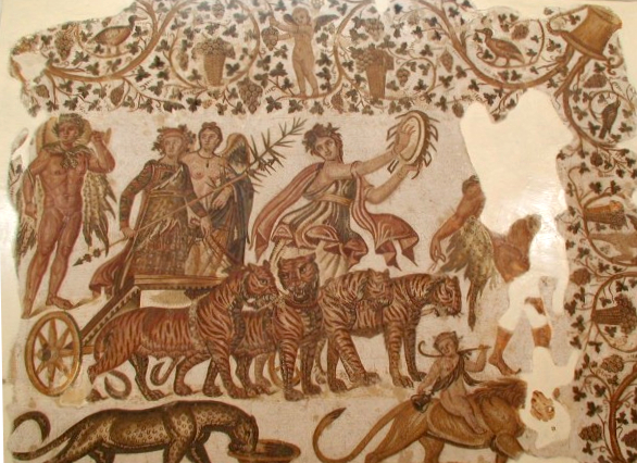 A parade. At the centre is a chariot pulled by wild cats, in which stand a winged naked man alongside a robed figure holding a large thyrsos. A woman dances and beats a drum in front of the chariot.