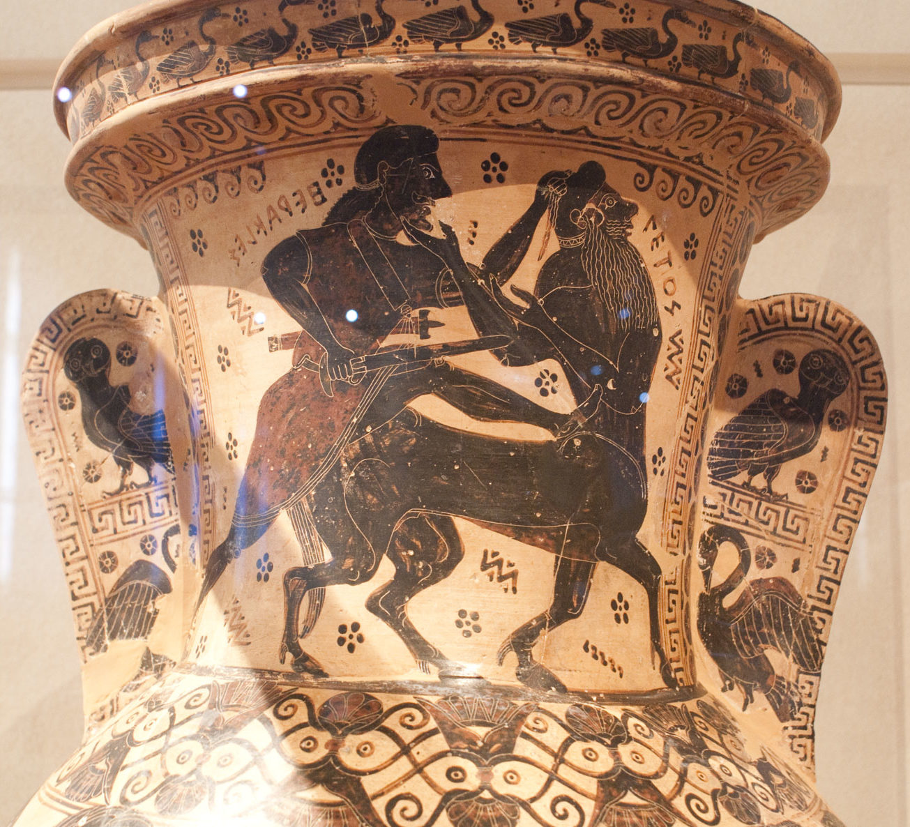 Heracles lunging at the centaur Nessus with a sword, kicking him in the back and grabbing his hair.