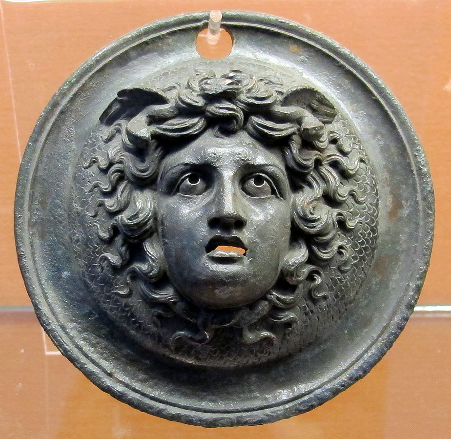 Head of Medusa as a young woman with curly hair and small wings on her head.