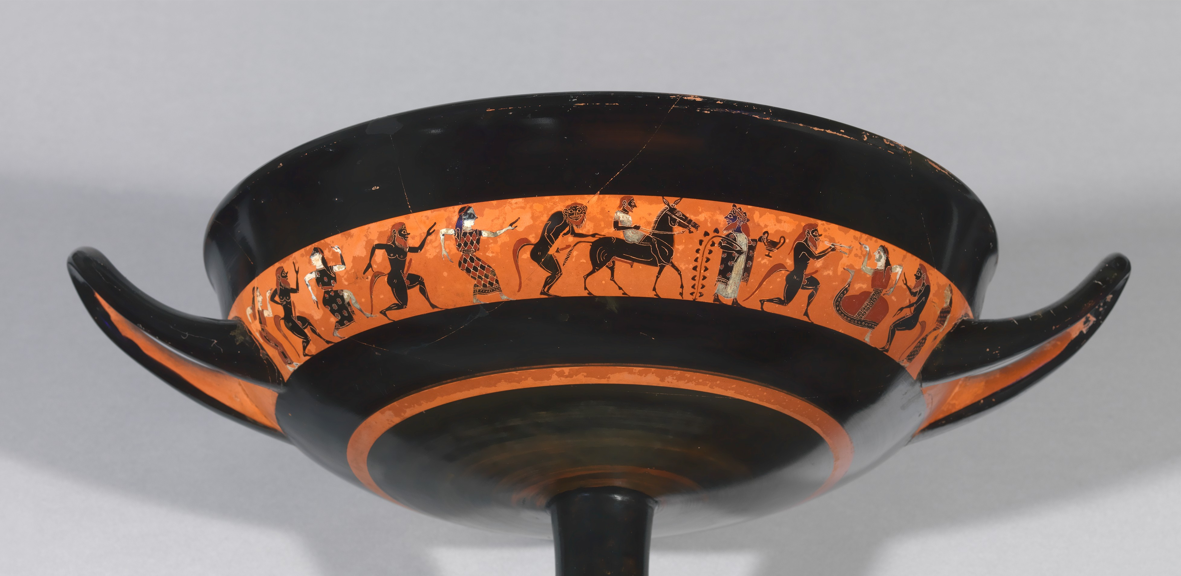 A procession of young maenad women and sileni. At the centre is Hephaestus, bearded, riding a mule, led by Dionysus, who holds a cup and grapevine.