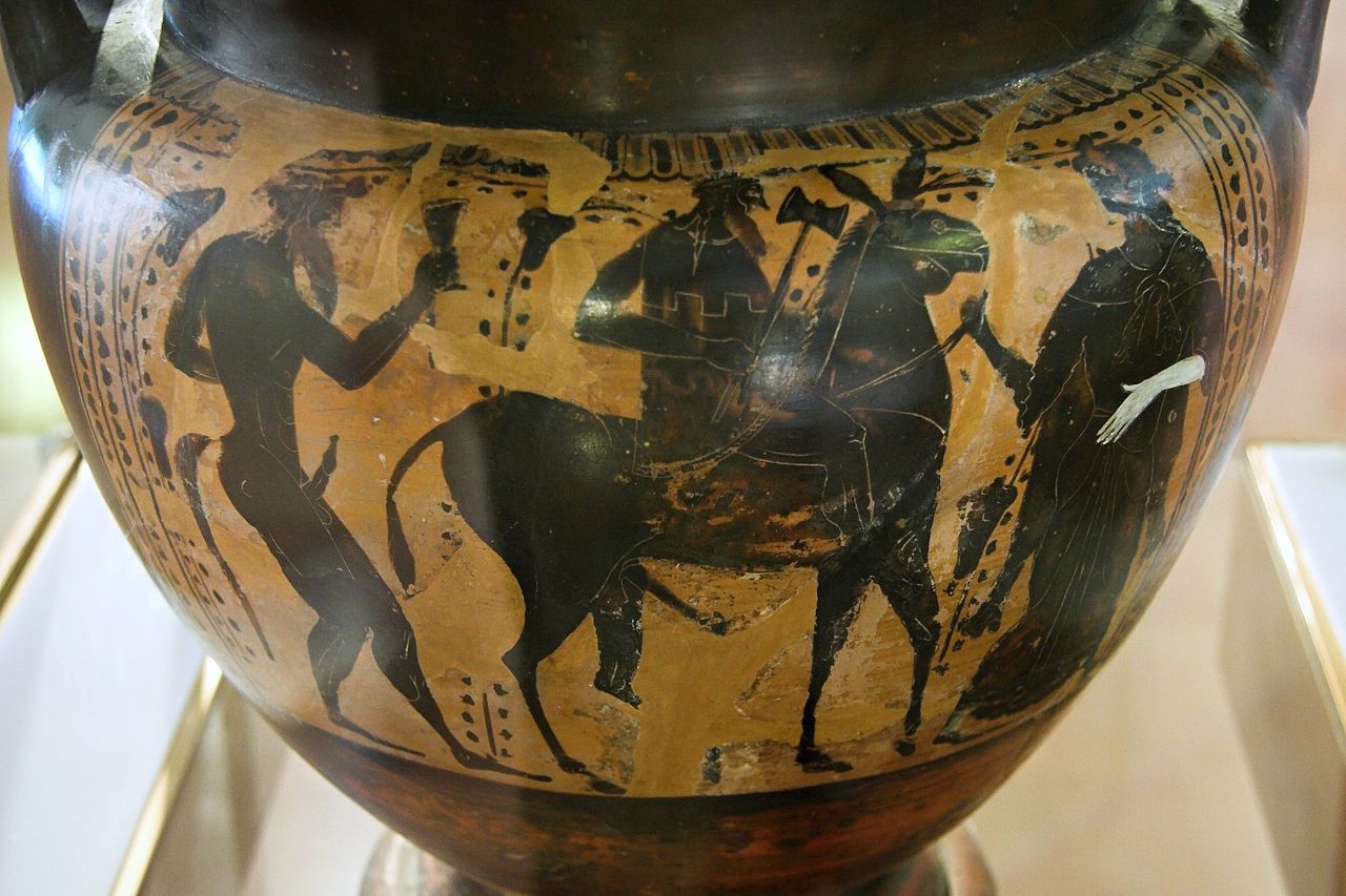 Hephaestus, holding a hammer, rides a mule. A silenus follows behind, and a young maenad woman walks ahead.