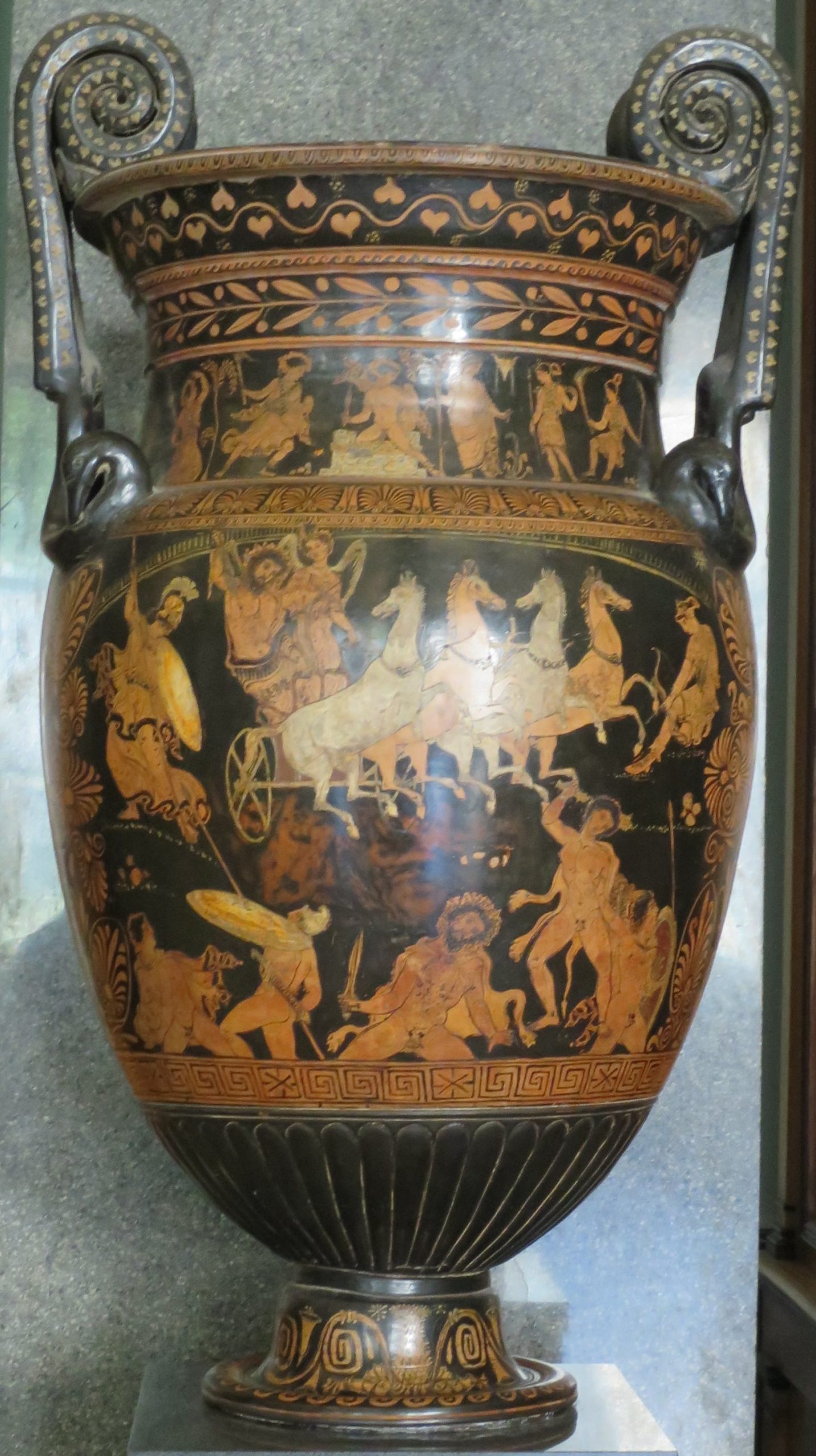 Zeus rides in a horse-drawn chariot. Other gods, including Athena, are around. Below them are the giants, armed with shields and various weapons, and nude.