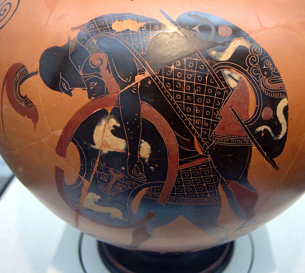 Ajax, carrying a painted shield, carries the body of Achilles over his back. Achilles wears full helm and armour, and has a shield decorated with a gorgoneion.