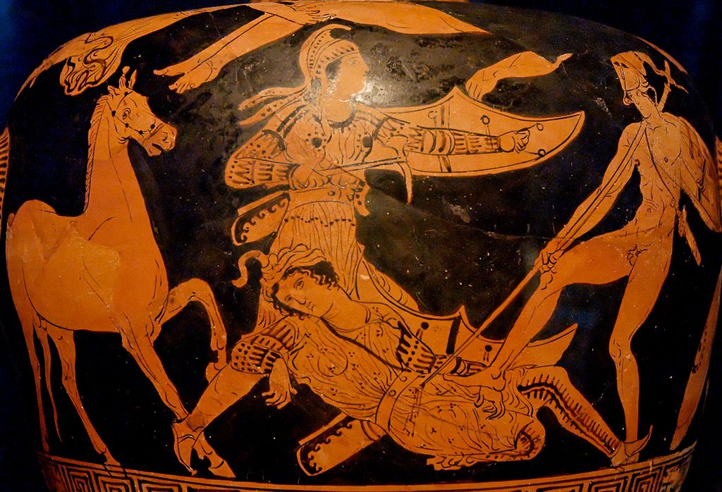 Patroclus, nude with helm, stabs Sarpedon with a spear. Sarpedon lies on the ground, wounded. He wears a wrapped cloth headdress, and a tunic over patterned leggings. Glaucus stands over Sarpedon with a crescent-shaped shield and pick to defend him. Glaucus wears a Phrygian cap, and a tunic over patterned leggings.