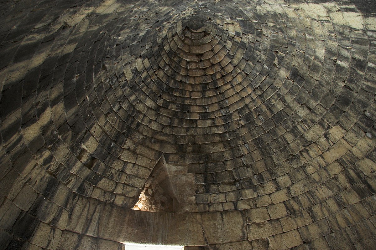 View looking up at the ceiling of the treasury of Atreus from inside. The ceiling is domed in the "Beehive/Tholos" tomb style. A small relief triangle is cut above where the doorway is.