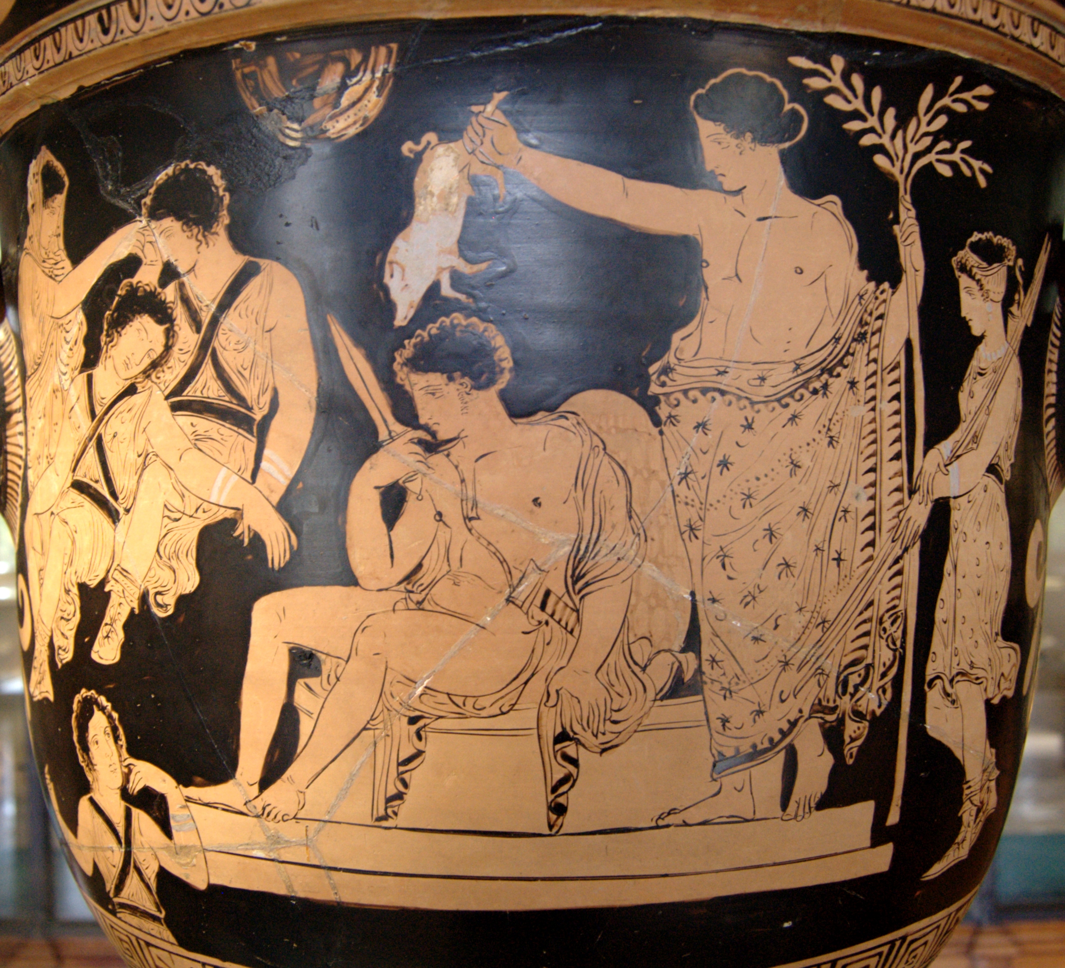Orestes, nude with chlamys cape and holding a knife, sits on an altar. Apollo, draped in a patterned himation, stands behind him holding a branch in one hand and a piglet over Orestes' head in the other. A young woman in a tunic stands behind Apollo. To the left, the three Furies, young women in tunics, sleep. Clytemnestra, veiled, sits beside them.