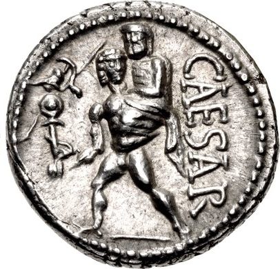 Silver coin. Aeneas advancing left, nude, holding father Anchises on shoulder with left hand, right hand holding small statue of Athena (the palladium). The word CAESAR in capitol Roman letters downward on right side.