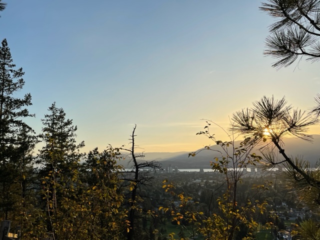 Sunset view of stqaʔtkʷɬcni̓wt or "windy bay" (Westbank) with pine and bushes in foreground