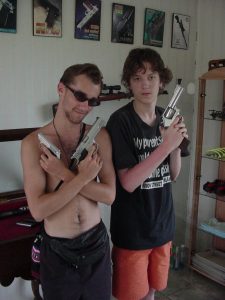 Two white boys posing with hand guns.