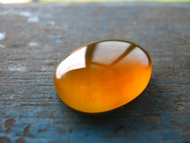 This piece of gold-colored amber from Malaysia has been rubbed and polished to a smooth, rounded shape.