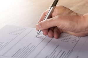 A person's hand completing a paper survey.