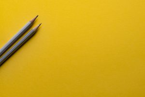 This picture shows two grey pencils with a yellow background.