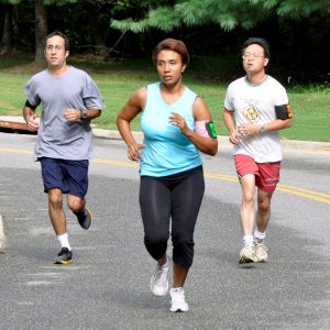 This picture shows a group of joggers running through a park.